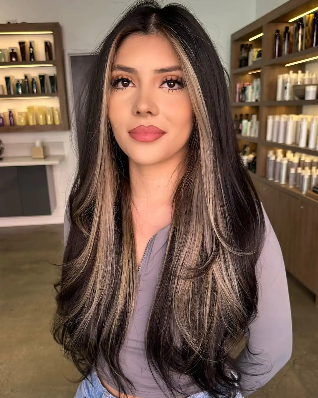 woman with long black hair and blonde face framing highlights in a salon