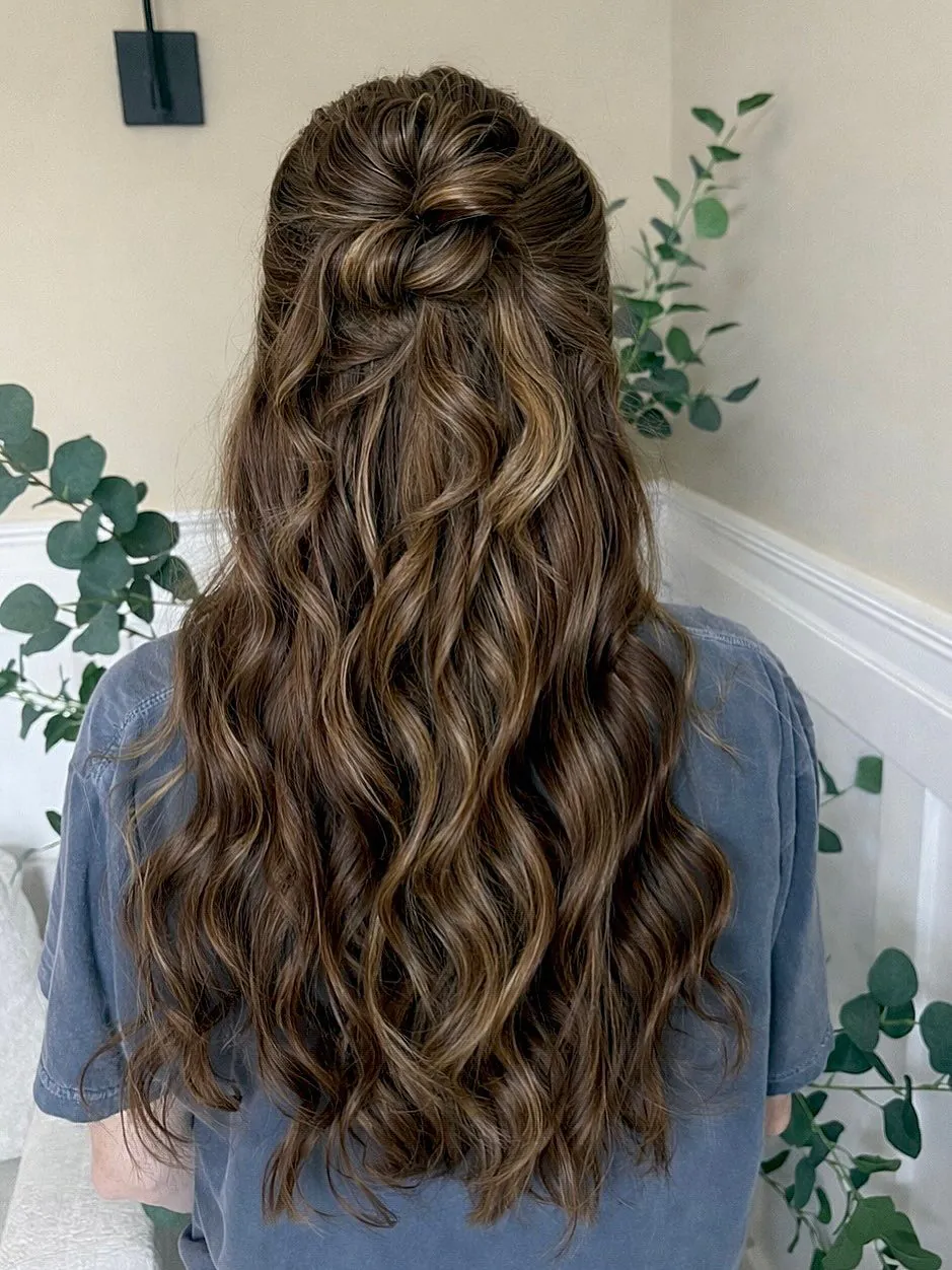long wavy brown hair with blonde highlights in a twisted half-up half-down style.