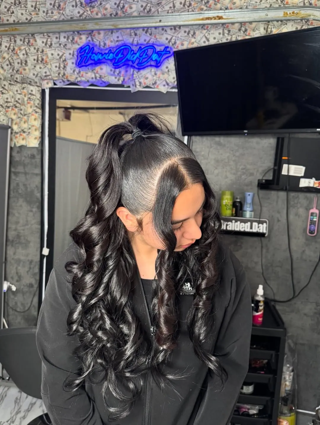 sleek black hair styled in a high half-up ponytail with voluminous bouncy curls.