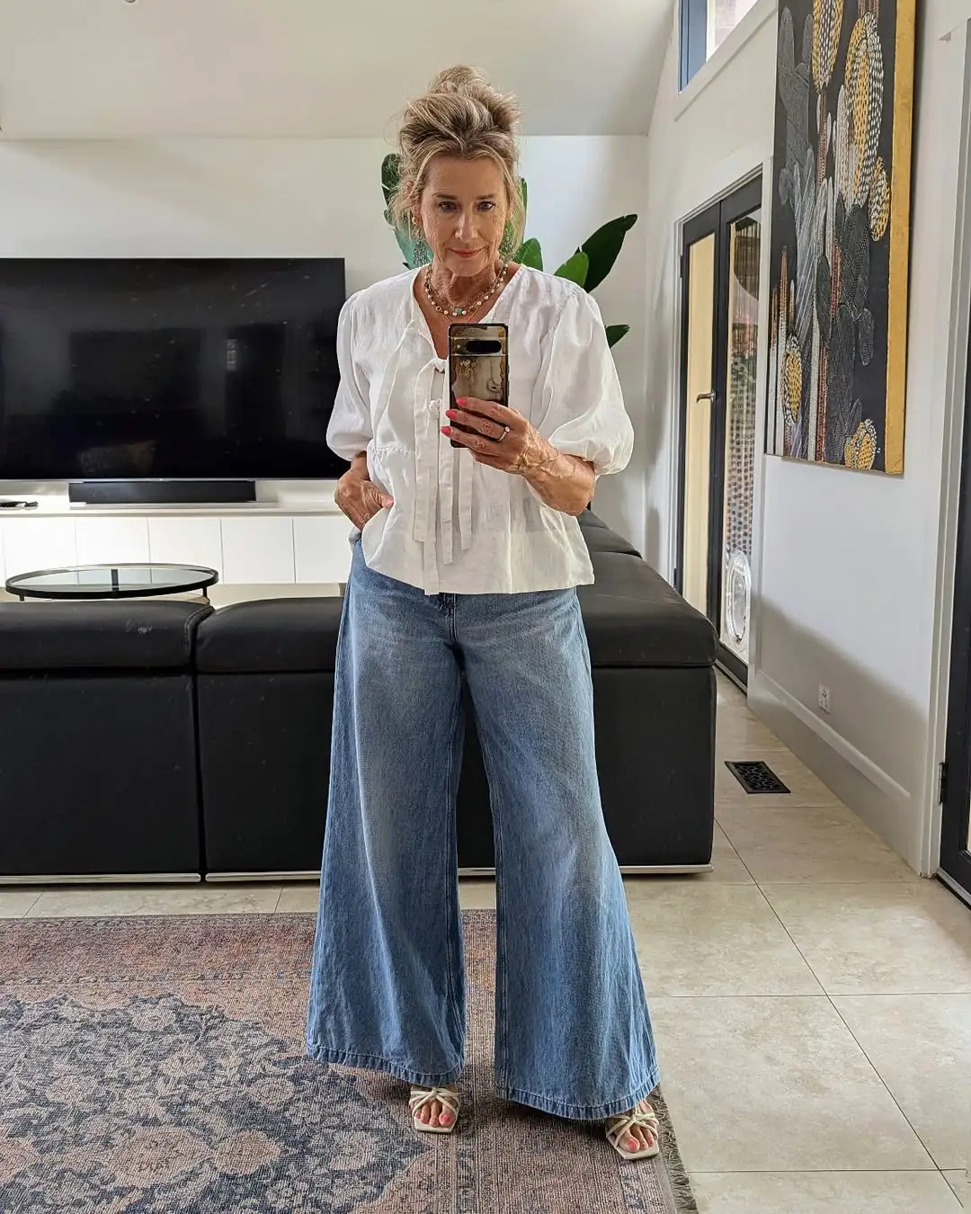 woman wearing white puff sleeve blouse and wide leg light wash jeans indoors