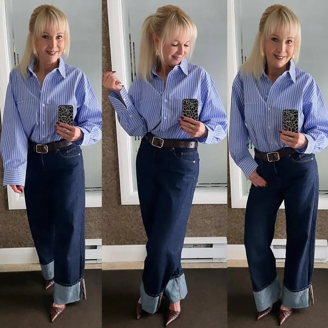 blonde woman wearing blue striped button down shirt tucked into cuffed dark wash jeans