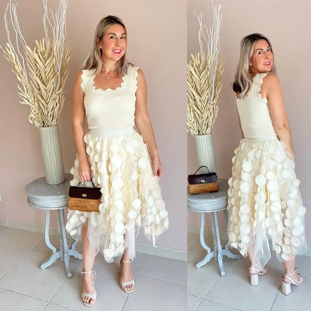 woman wearing cream scalloped tank top and white textured applique midi skirt.