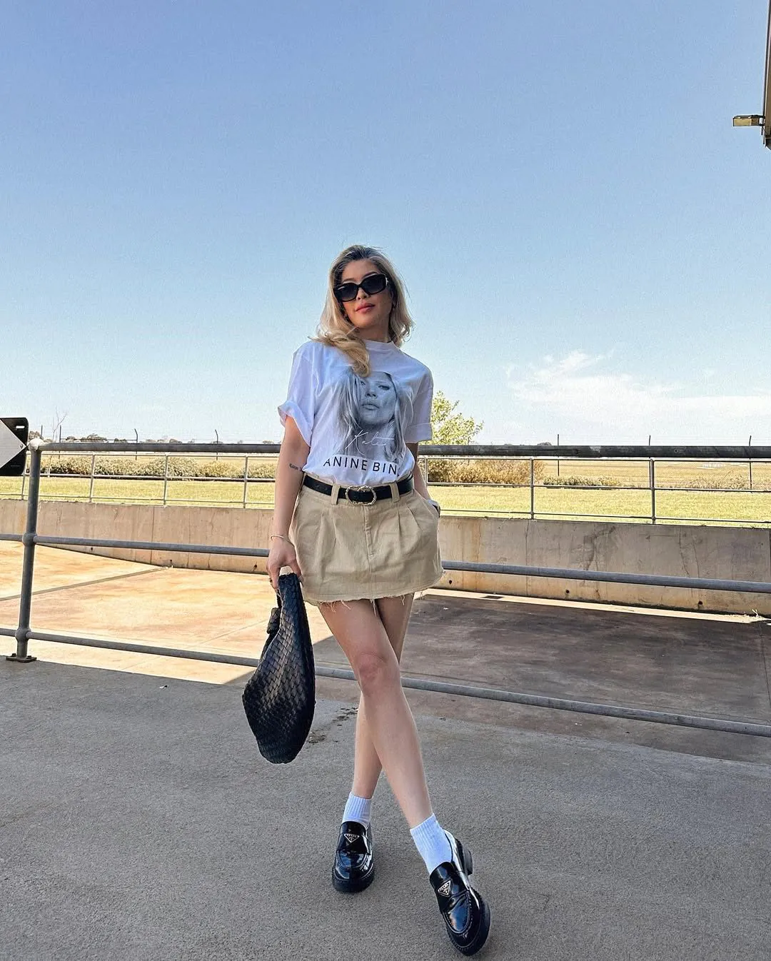 woman wearing white graphic t-shirt and tan corduroy mini skirt with black loafers.