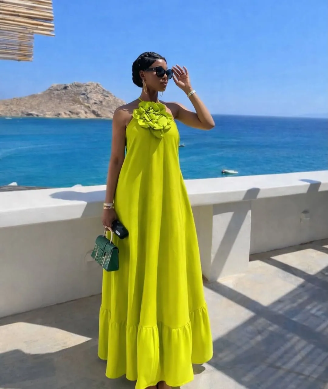 woman in a lime green halter dress with floral detail overlooking the ocean