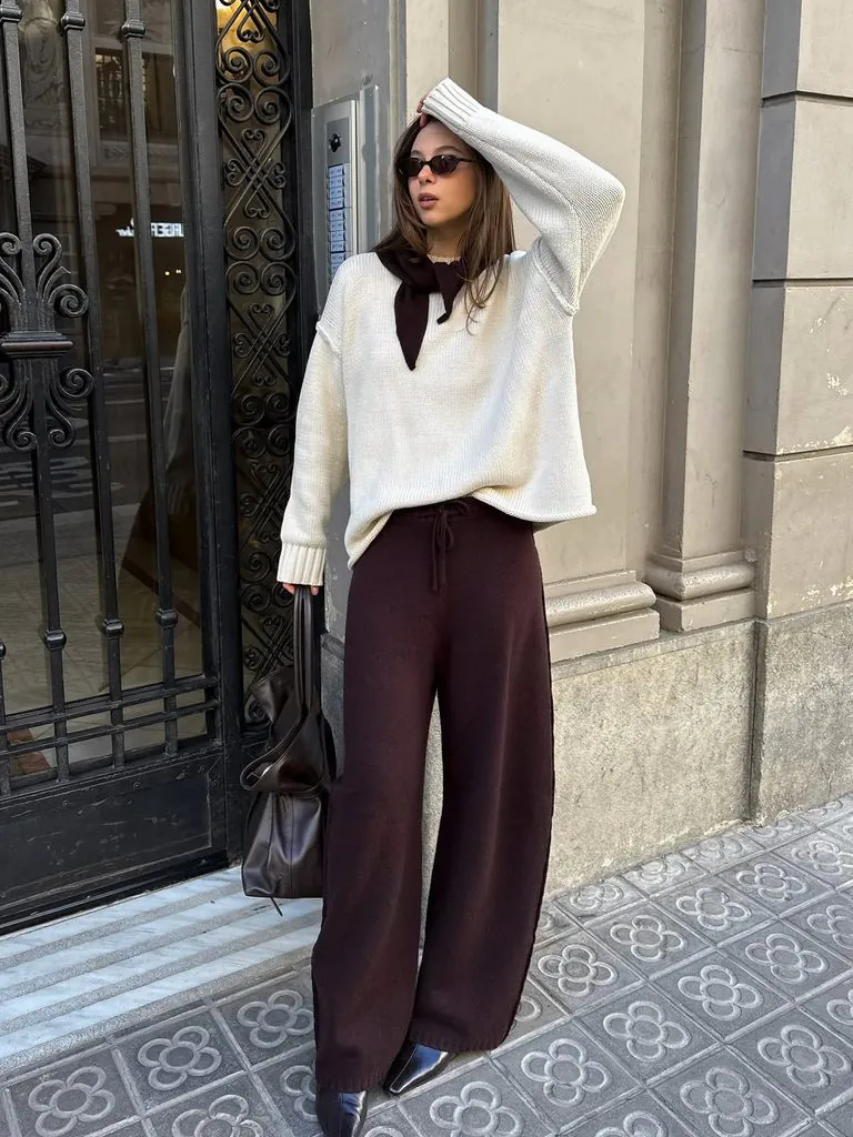 woman wearing oversized white sweater and dark brown wide leg pants outdoors