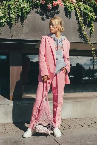 woman wearing stylish pink pantsuit and grey hoodie on a city street