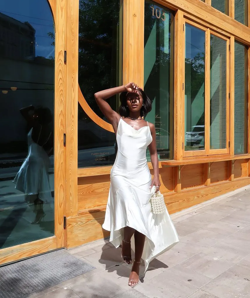black woman in a white satin high-low slip dress all-white party outfit