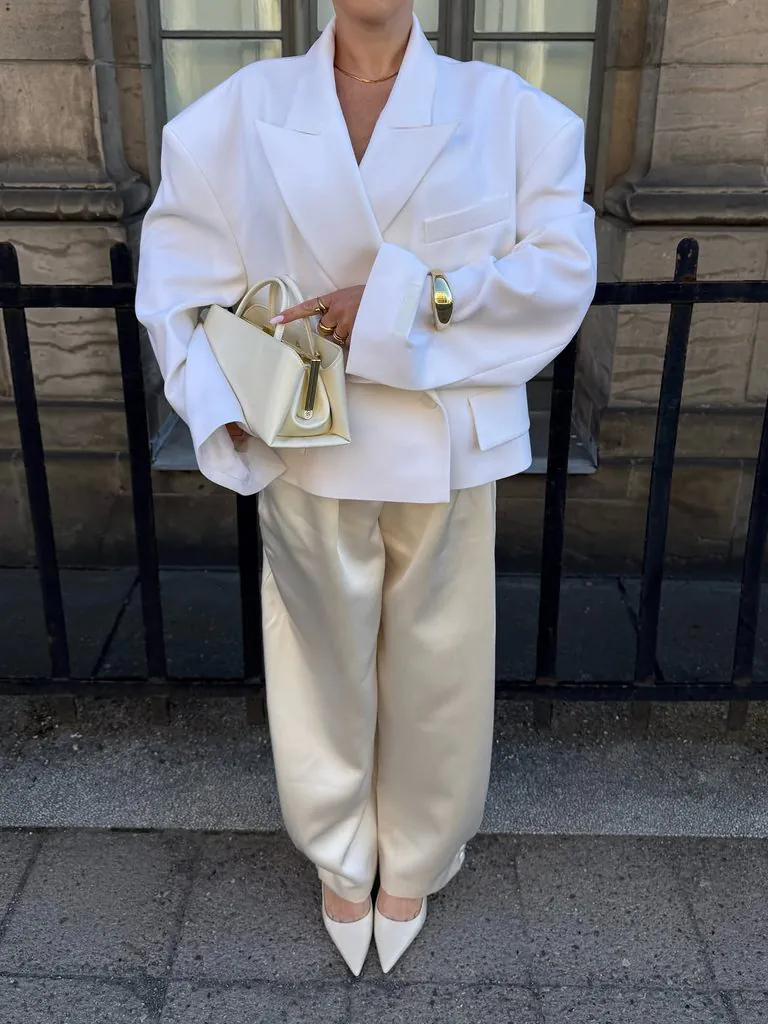 person wearing an oversized white blazer and satin pants all-white party outfit