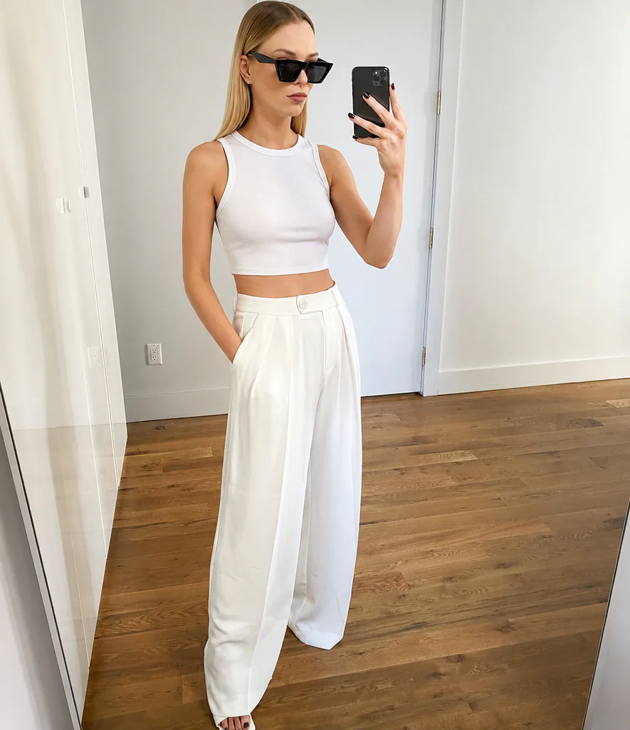 blonde woman wearing a white crop top and wide-leg trousers all-white party outfit