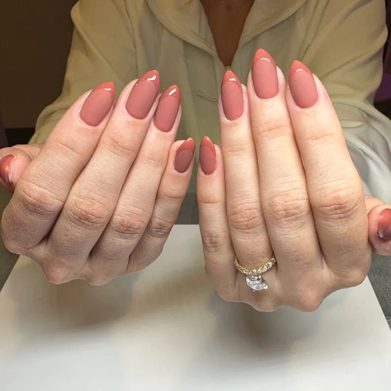 almond shaped nails with a matte terracotta base and glossy french tips