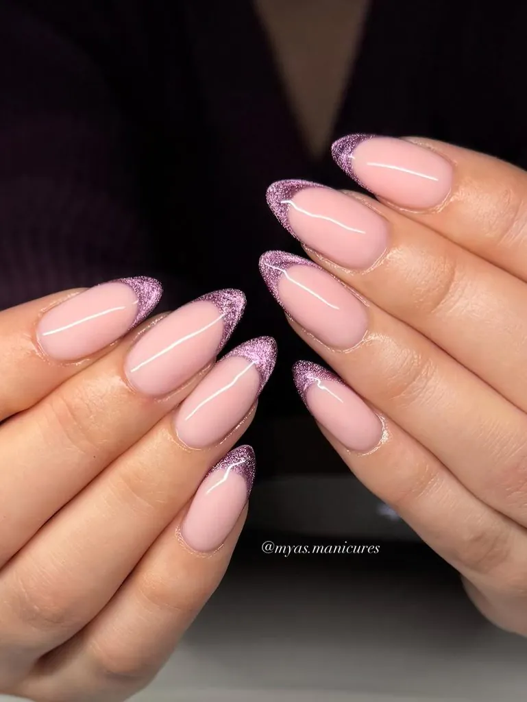 almond shaped nude manicure featuring sparkly purple cat eye french tip nails