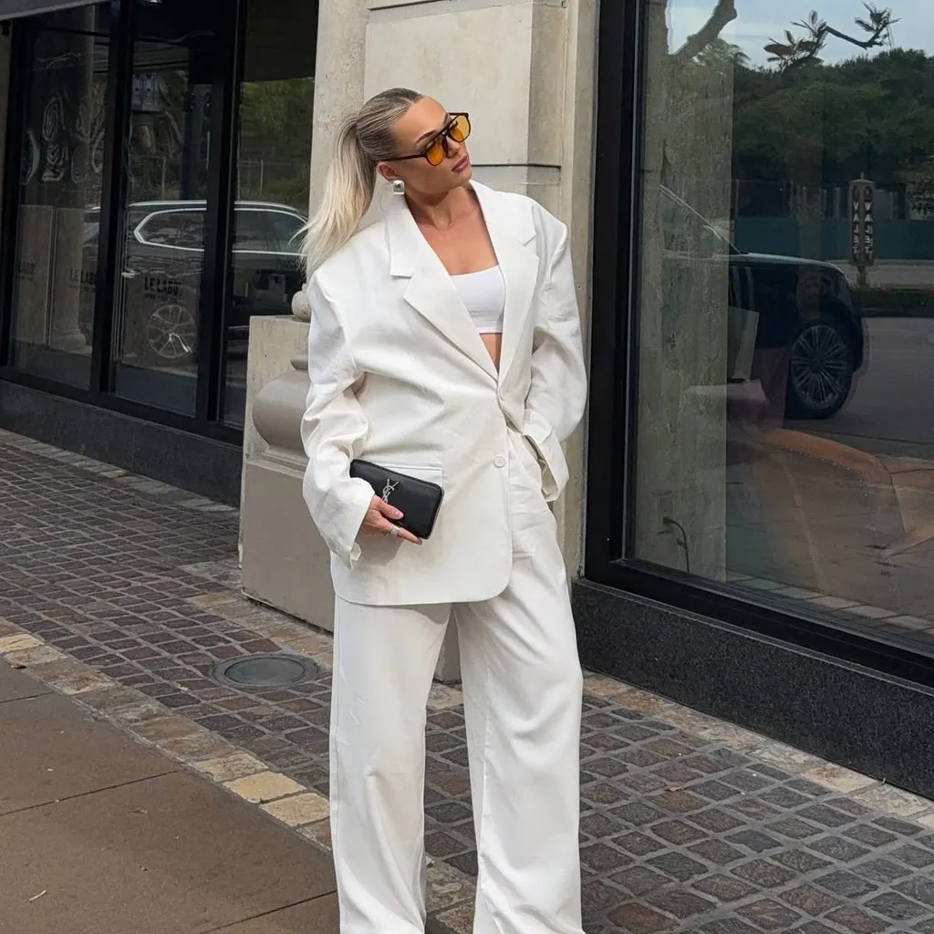 woman wearing an oversized white pantsuit and a crop top for a concert outfit