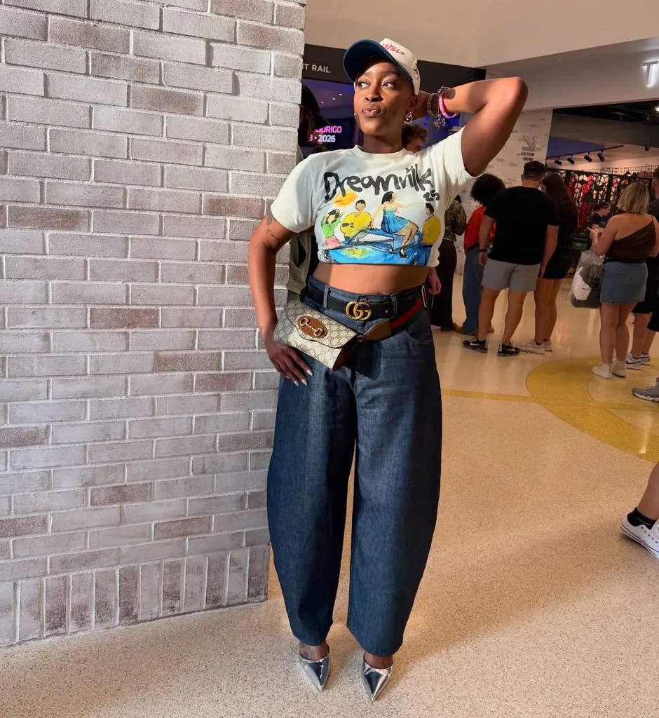 woman wearing a graphic crop top, wide-leg jeans, and metallic heels as a concert outfit