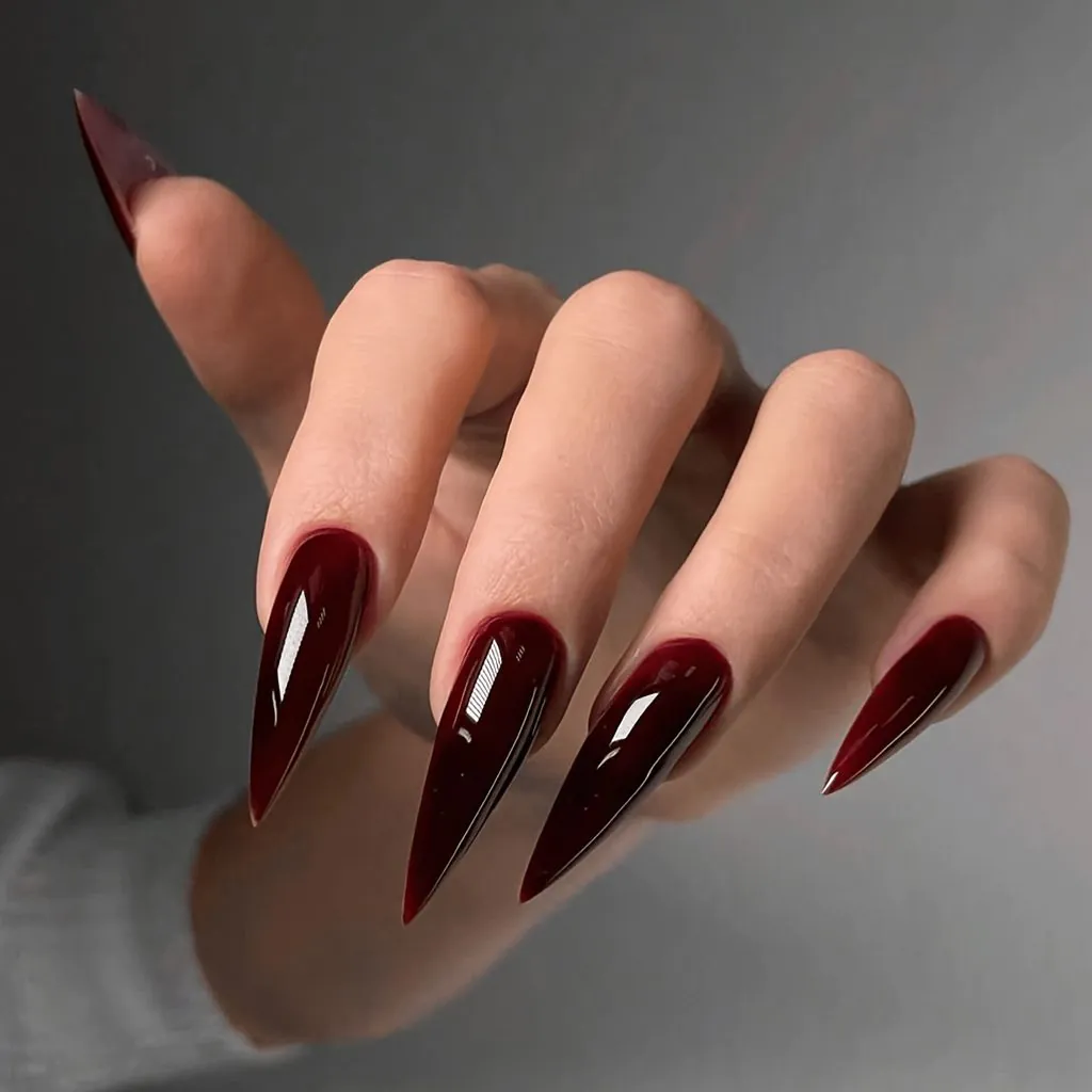 long sharp stiletto fall nails painted in a glossy deep burgundy red polish