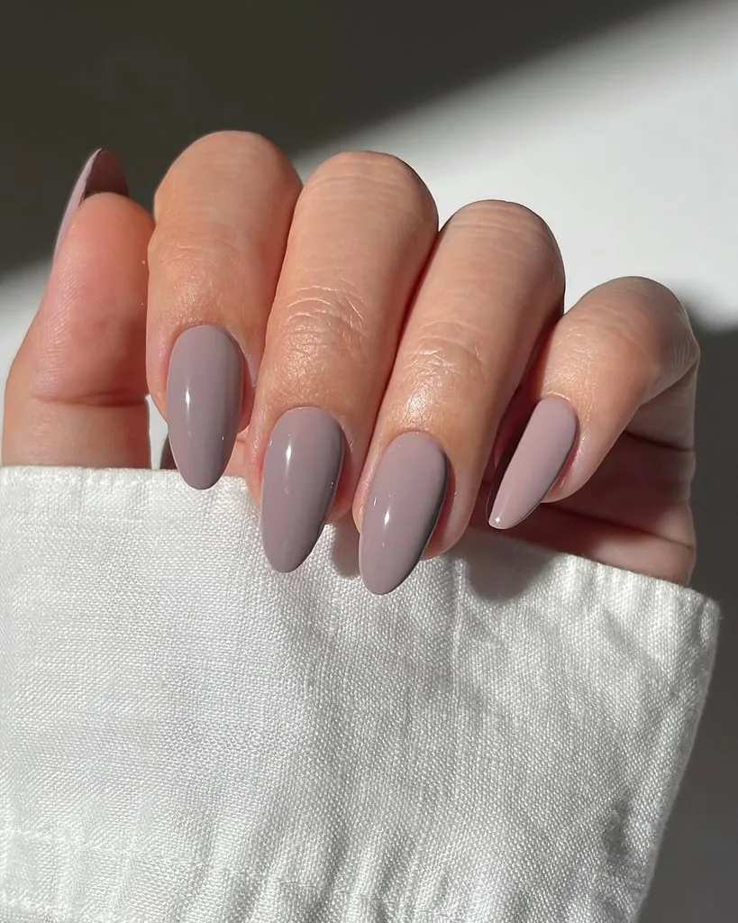 glossy muted mauve taupe purple manicure on elegant almond shaped nails