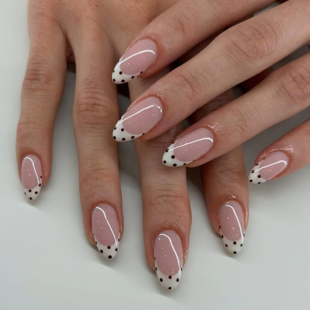 almond shaped manicure with white french tip nails decorated with black polka dots