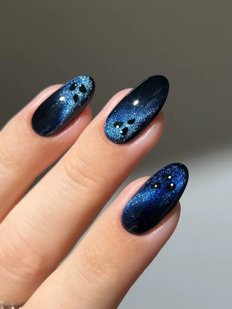 cat eye blue glitter nails featuring black ghost face nail art designs