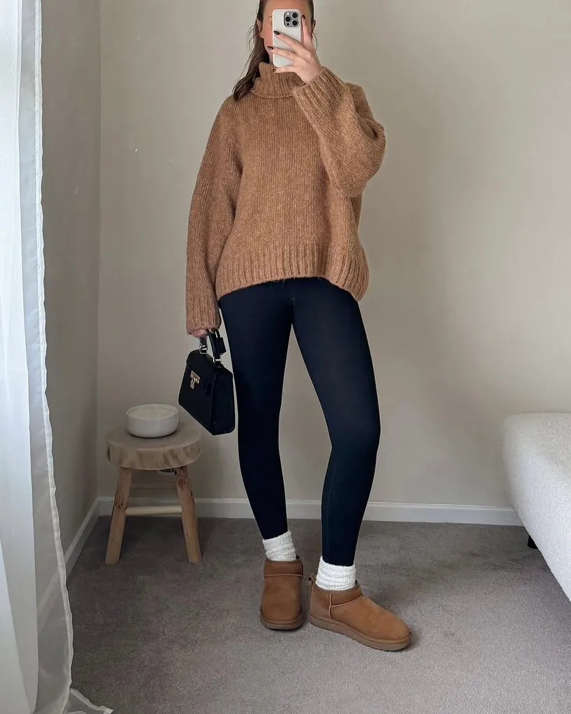 woman in black leggings, oversized brown turtleneck sweater, and brown mini boots
