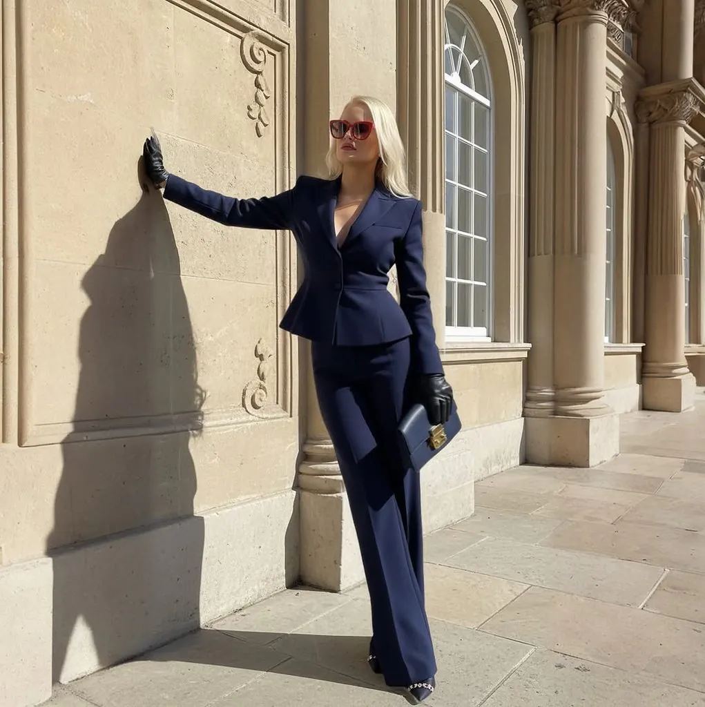 woman wearing a navy blue tailored suit with sunglasses and gloves