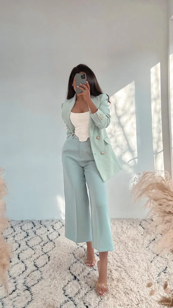 woman posing in a light blue pantsuit tea party outfit taking a mirror selfie