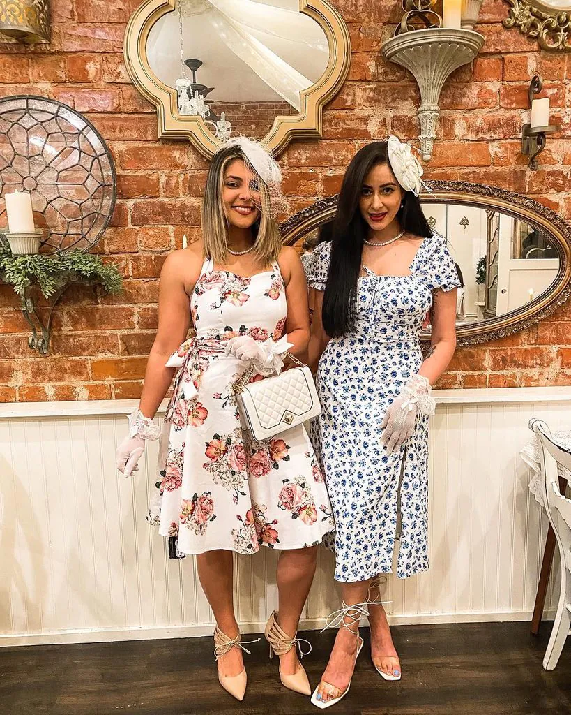 two women in floral tea party outfits wearing fascinators and lace gloves