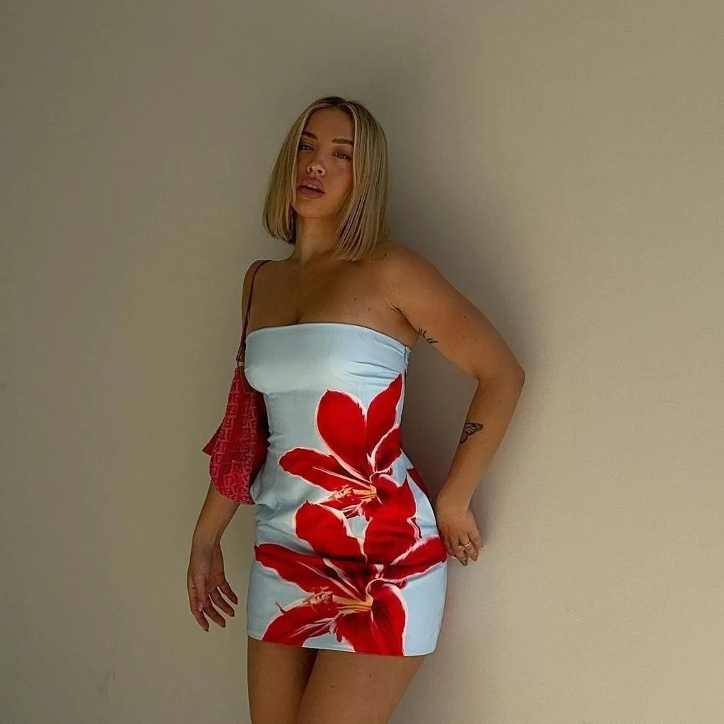 woman wearing a strapless light blue mini dress with a large red floral print