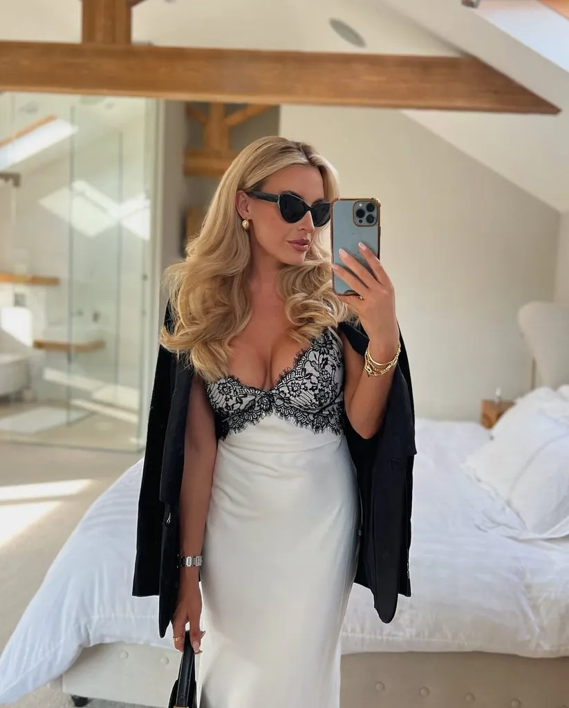 woman wearing a white silk slip dress with black lace trim and a black blazer