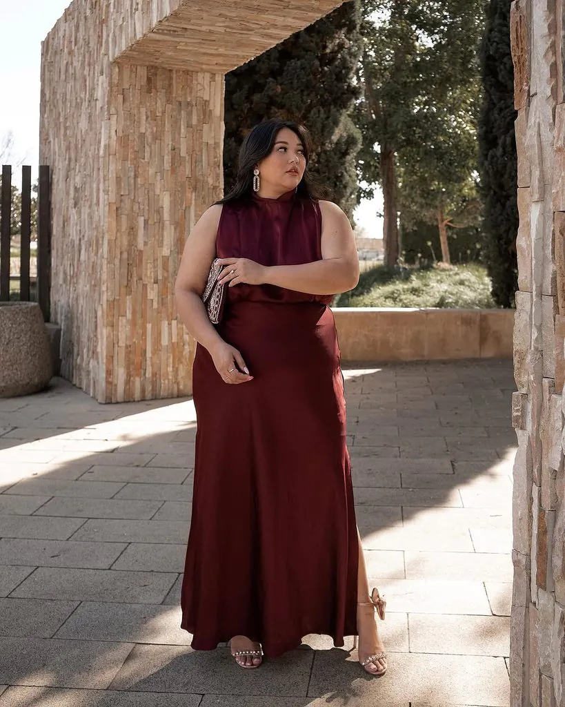 plus size woman posing in a burgundy satin maxi dress outdoors