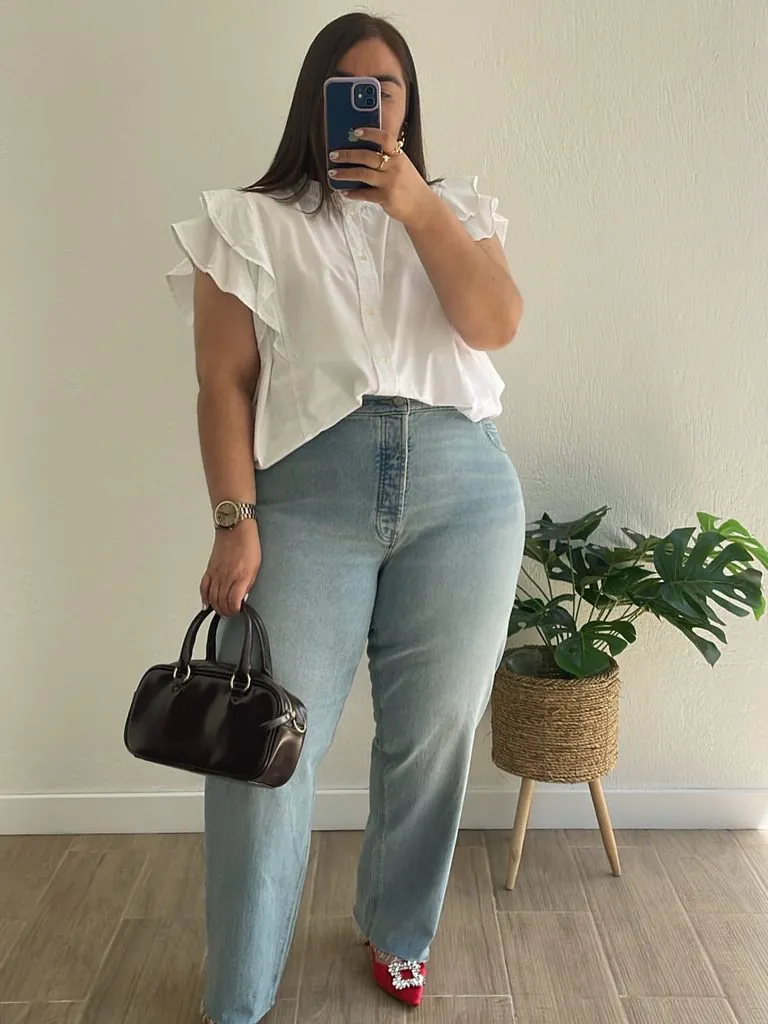 plus size woman wearing a white ruffled shirt and light blue jeans