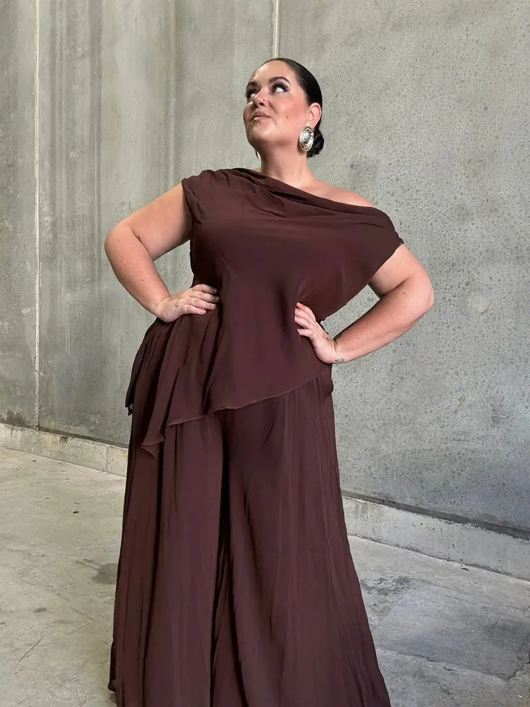plus size woman posing in a brown off the shoulder jumpsuit
