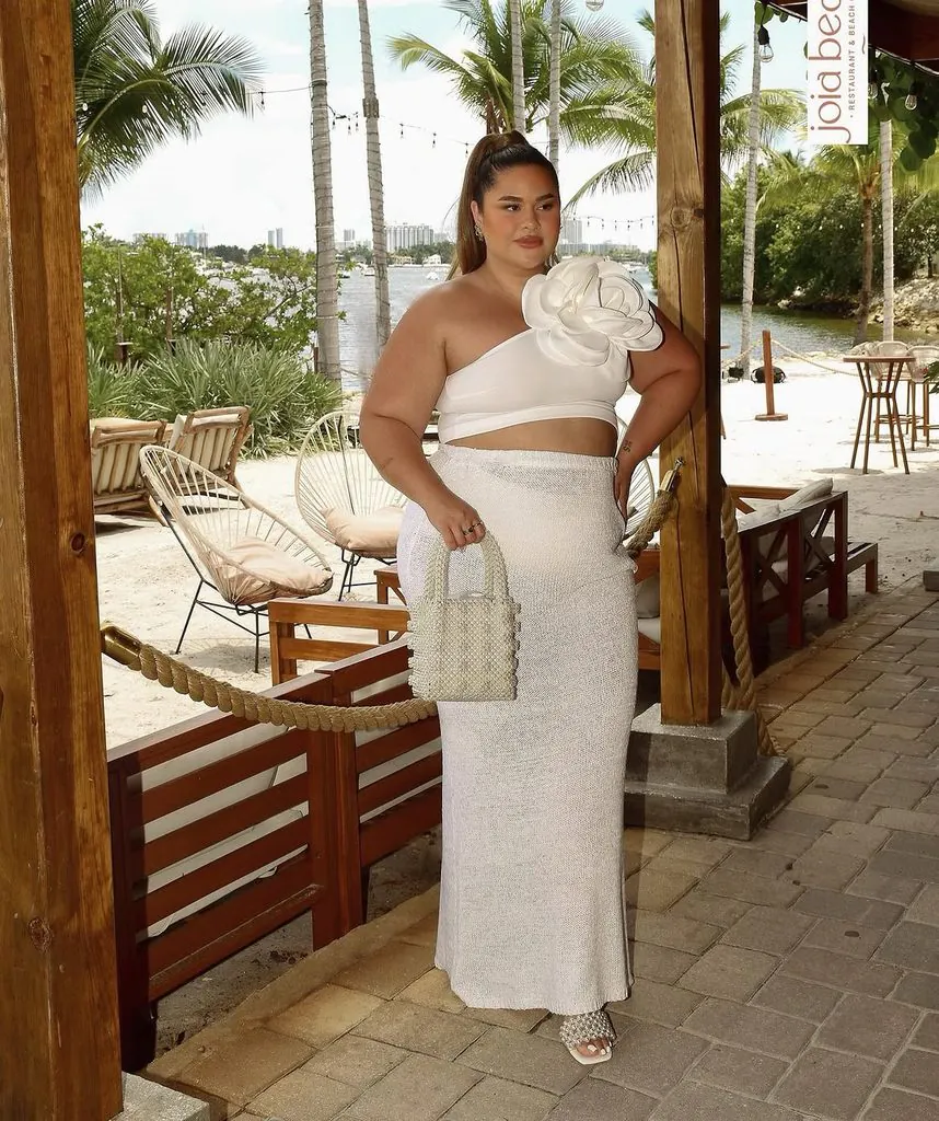 plus size woman wearing a white flower top and maxi skirt on the beach