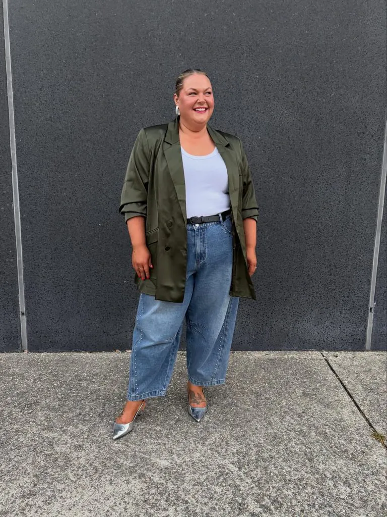 plus size woman wearing an olive green blazer and jeans outdoors