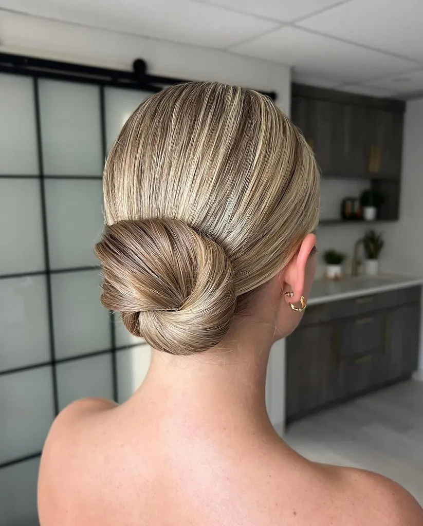 blonde woman with a sleek low twisted bun hairstyle in a modern salon setting
