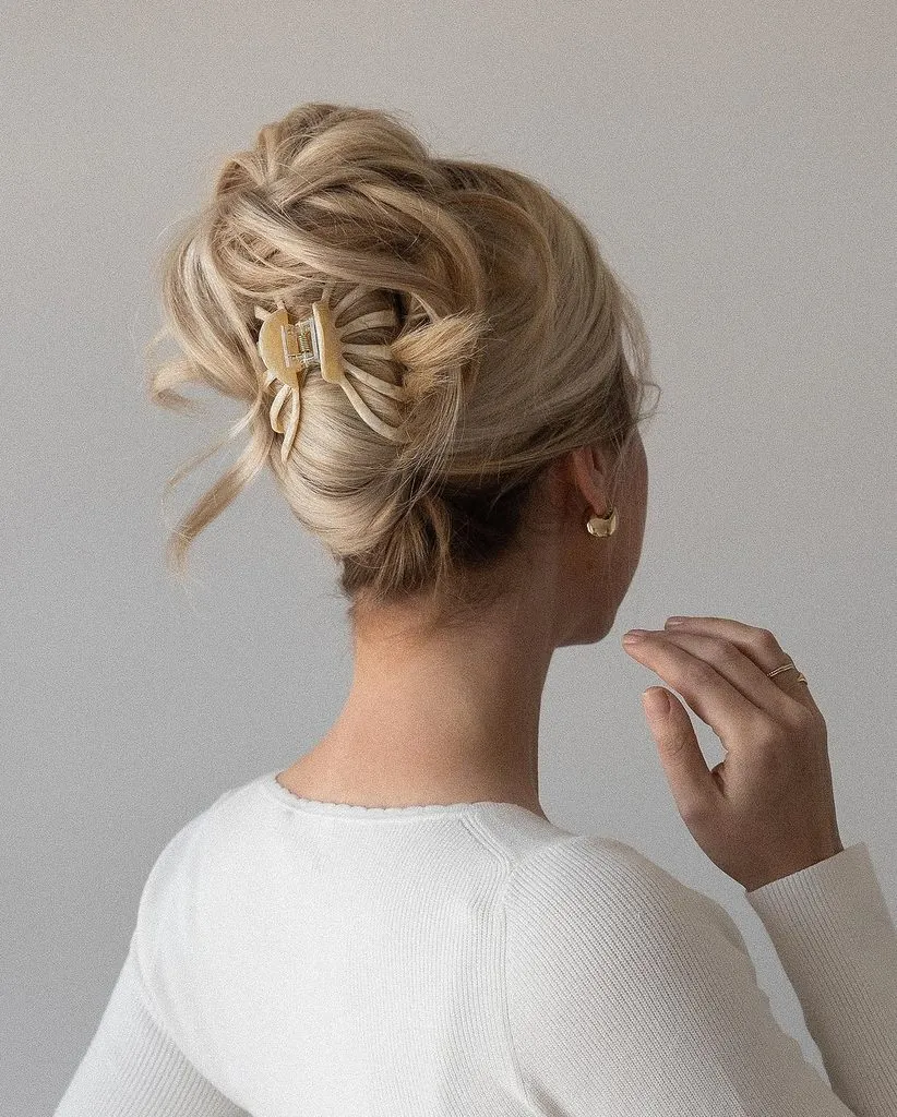 blonde woman wearing a messy updo hairstyle secured with a beige claw clip