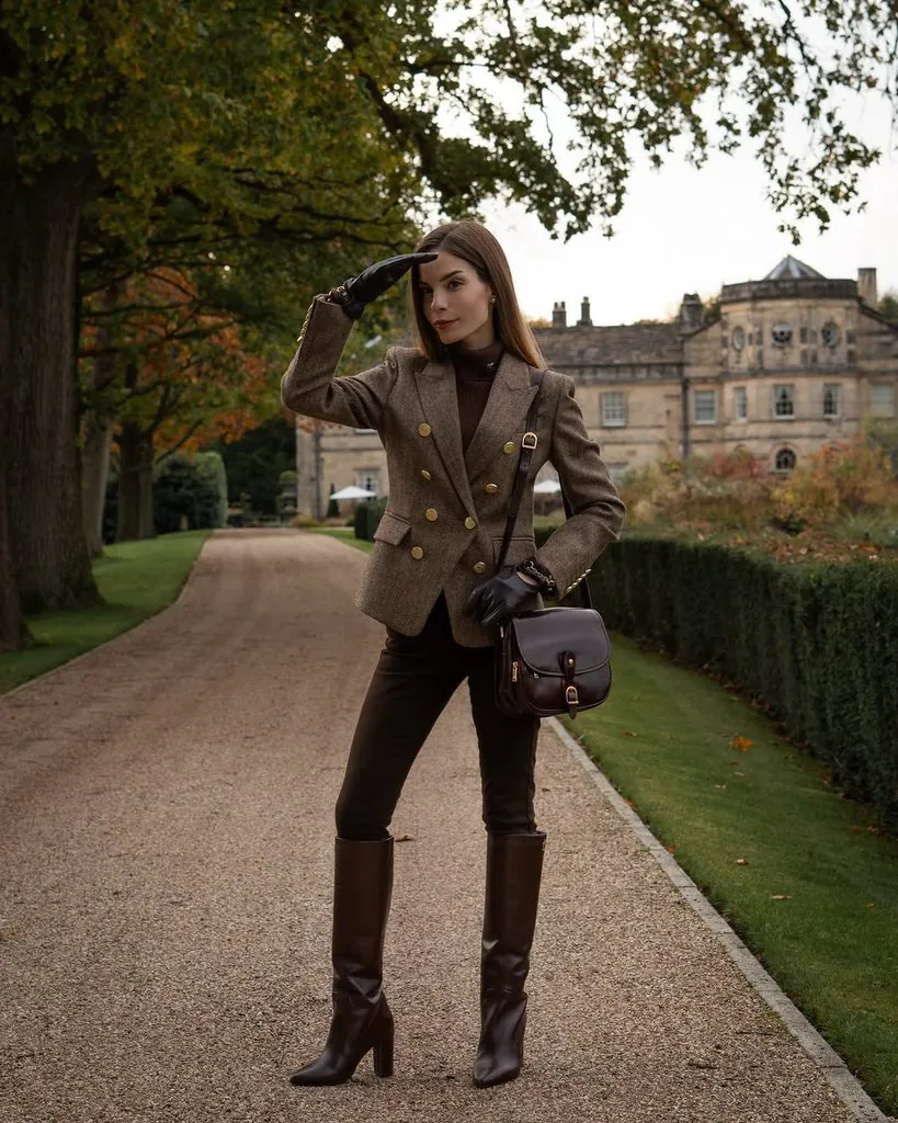 woman in brown tweed blazer and tall boots standing in driveway