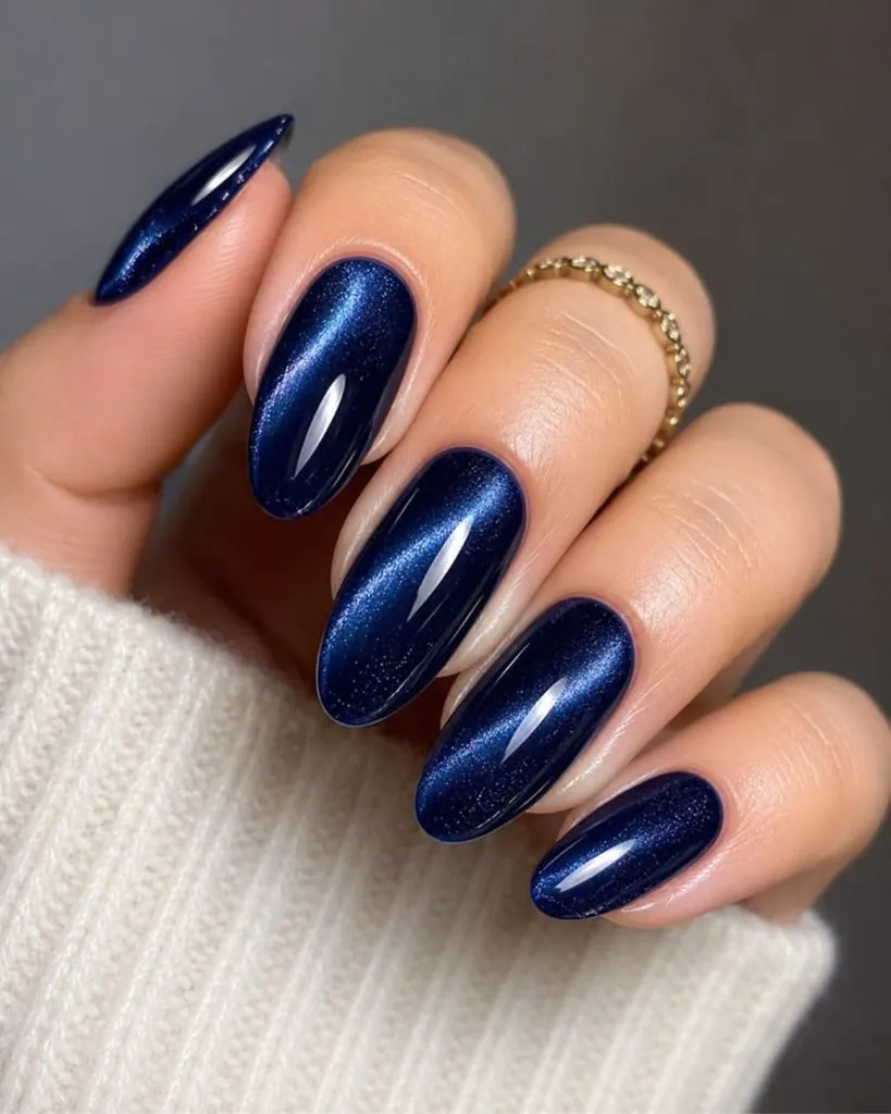 shimmer shimmer navy blue cat eye almond nails with a gold ring