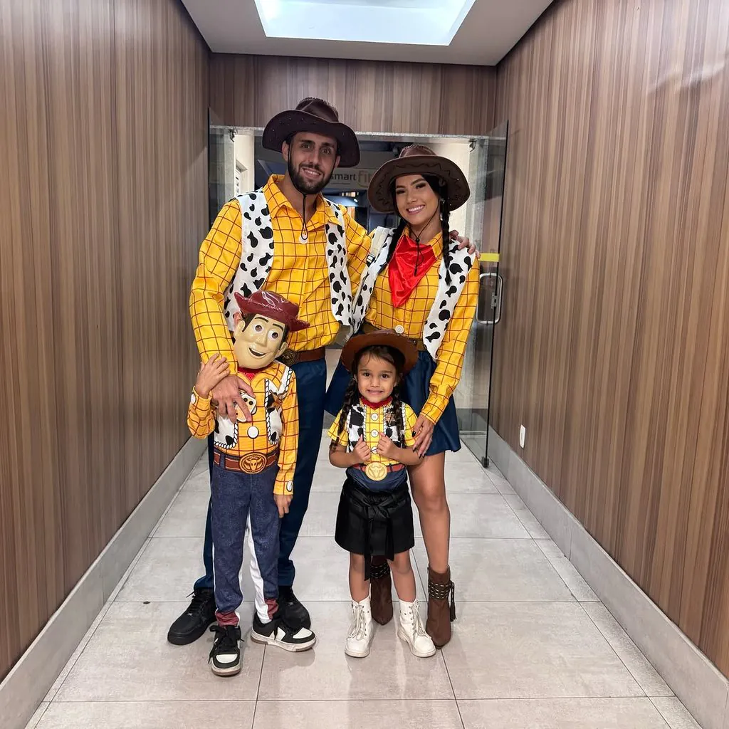 family wearing matching toy story woody costumes posing together in a wooden hallway
