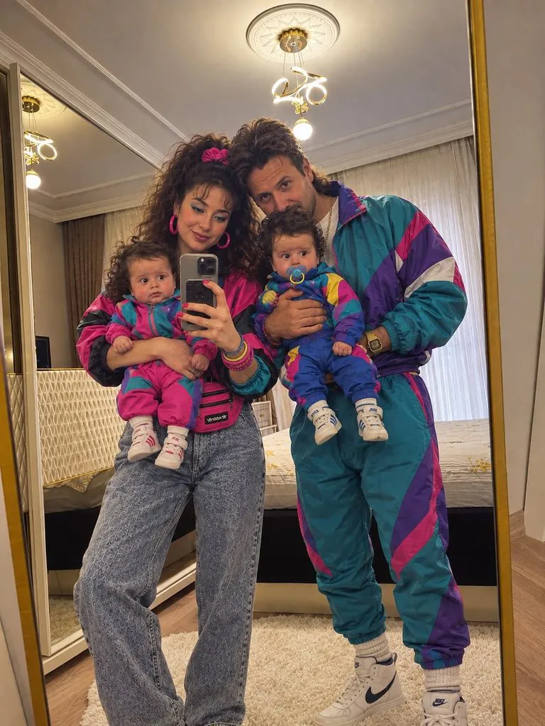 family holding twin babies all wearing matching retro 80s colorful tracksuits