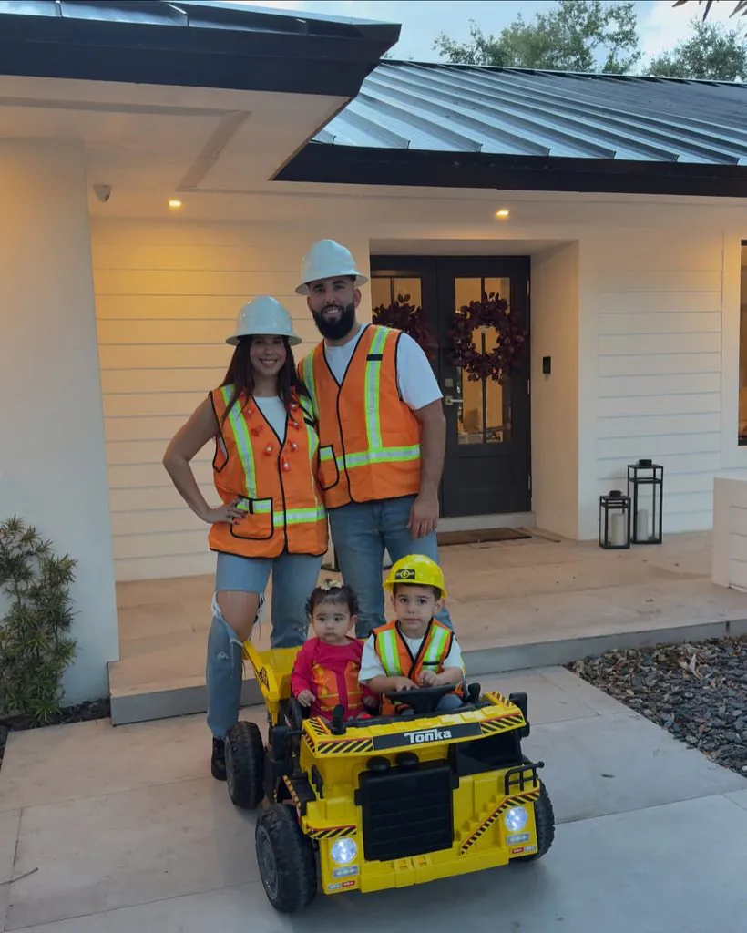 family dressed as construction workers posing with a yellow toy dump truck