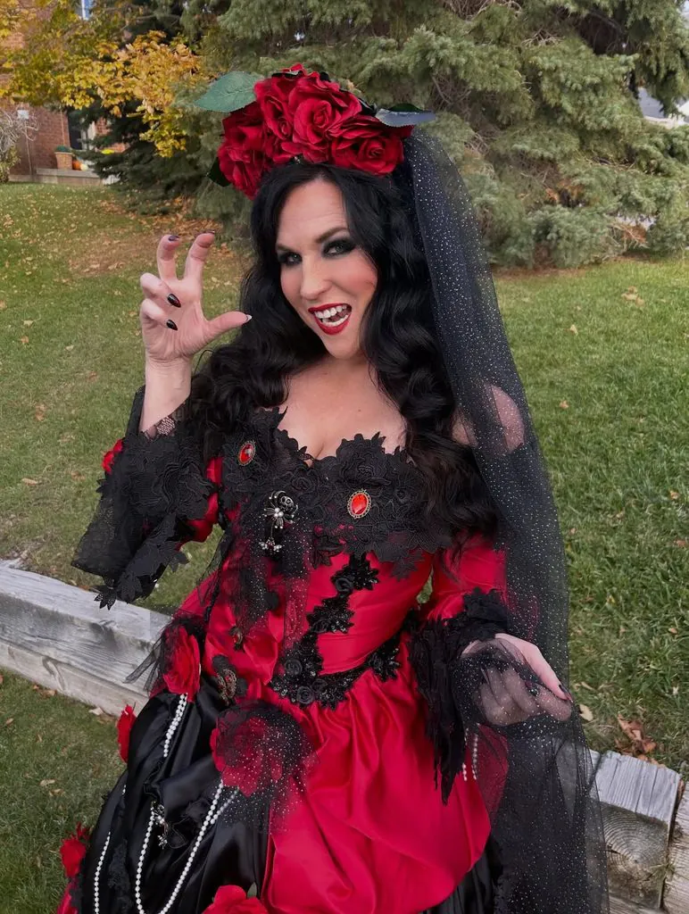woman wearing a gothic vampire costume with a red dress black veil and rose headpiece