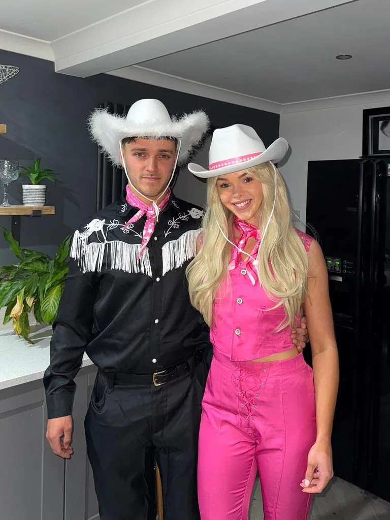 couple wearing pink and black cowboy halloween costumes standing side by side