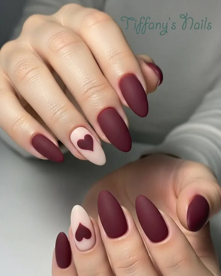 matte plum almond nails with a light pink heart accent nail
