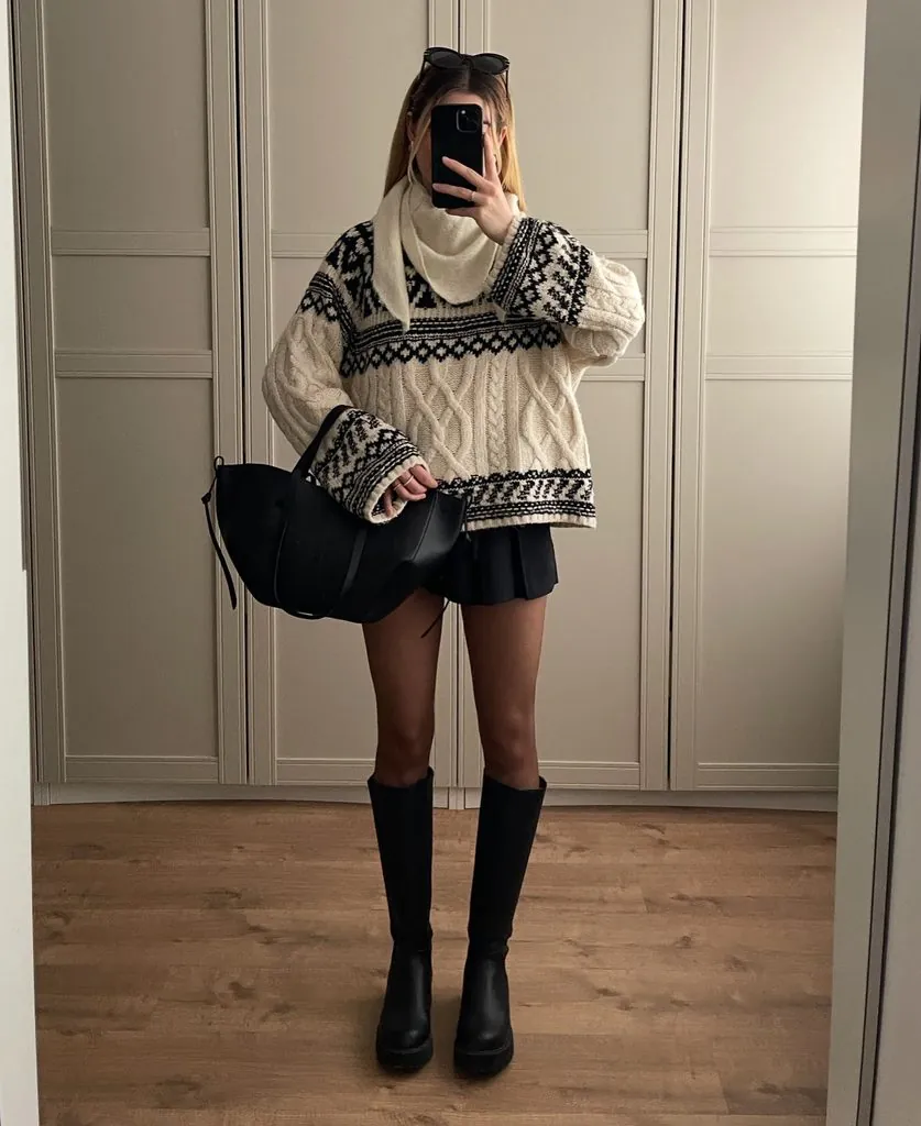 woman in cream pattern knit sweater black skirt and knee high leather boots